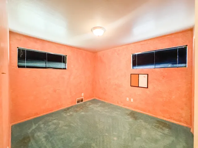 Interior room featuring textured walls, two windows with horizontal blinds, and ceiling-mounted lighting