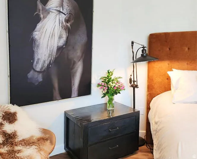 Warm wood-finish flooring complements the upholstered headboard, creating a cohesive aesthetic