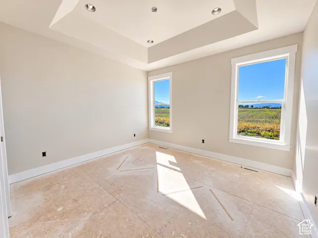 Recessed lighting, tray ceiling, two large windows, white trim, and light wall paint
