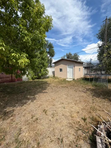 Spacious backyard featuring a detached storage shed, mature trees, and fencing