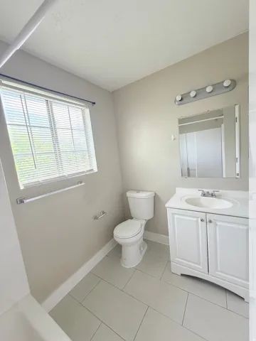 Bathroom with light gray tile flooring and a window with blinds