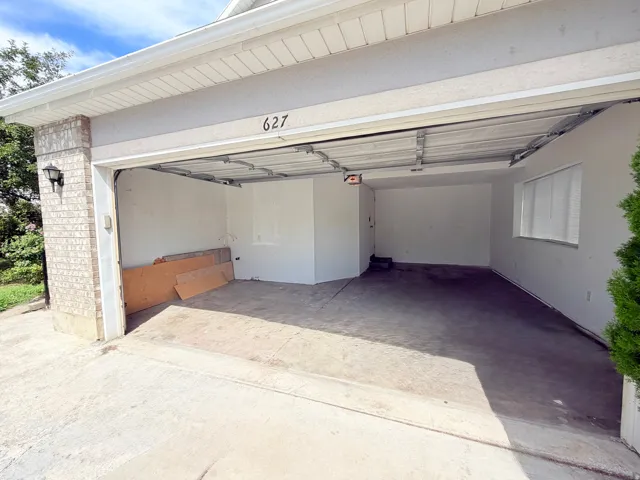 Two-car garage with concrete flooring, stucco exterior, and brick accents