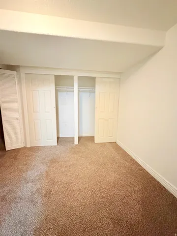 Wall-to-wall carpeting with a light brown hue, complemented by white baseboards and walls