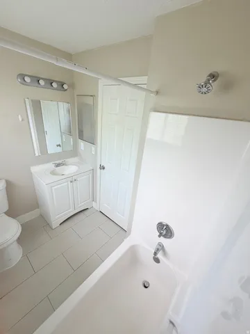 Contemporary bathroom featuring a white vanity with integrated sink, rectangular mirror, and light gray rectangular floor tiles