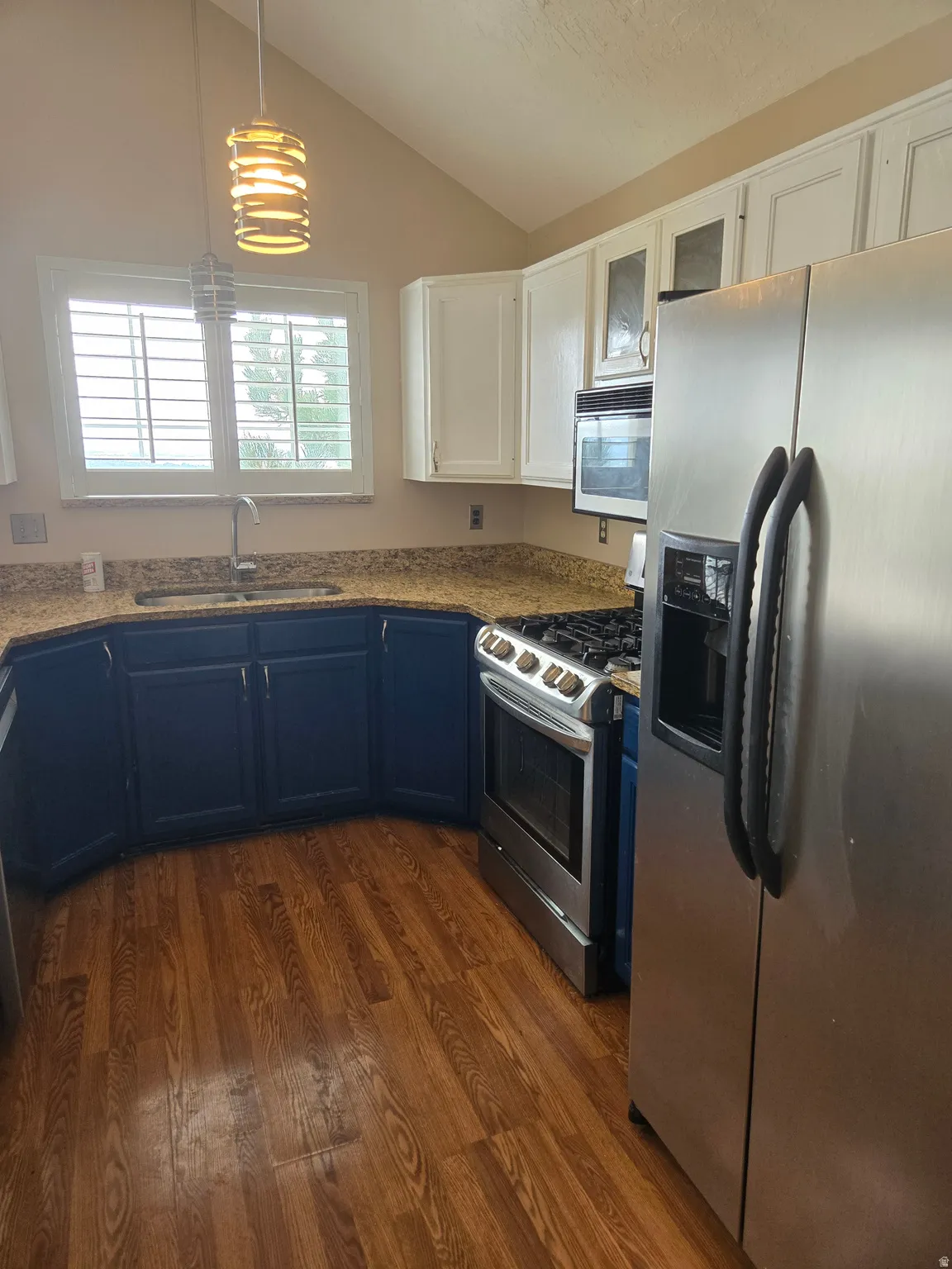 Kitchen featuring wood-finish flooring, white upper cabinetry, blue lower cabinetry, and granite countertops