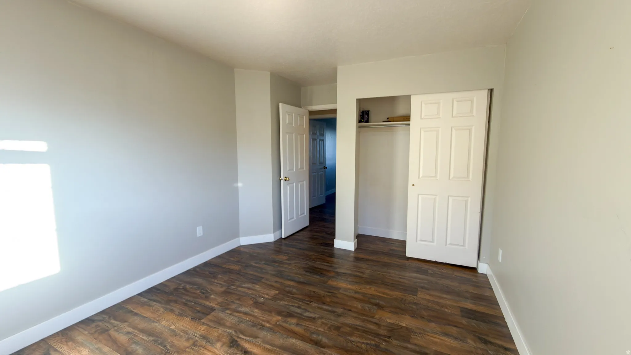 Room featuring wood-finish flooring, light gray wall paint, and white trim