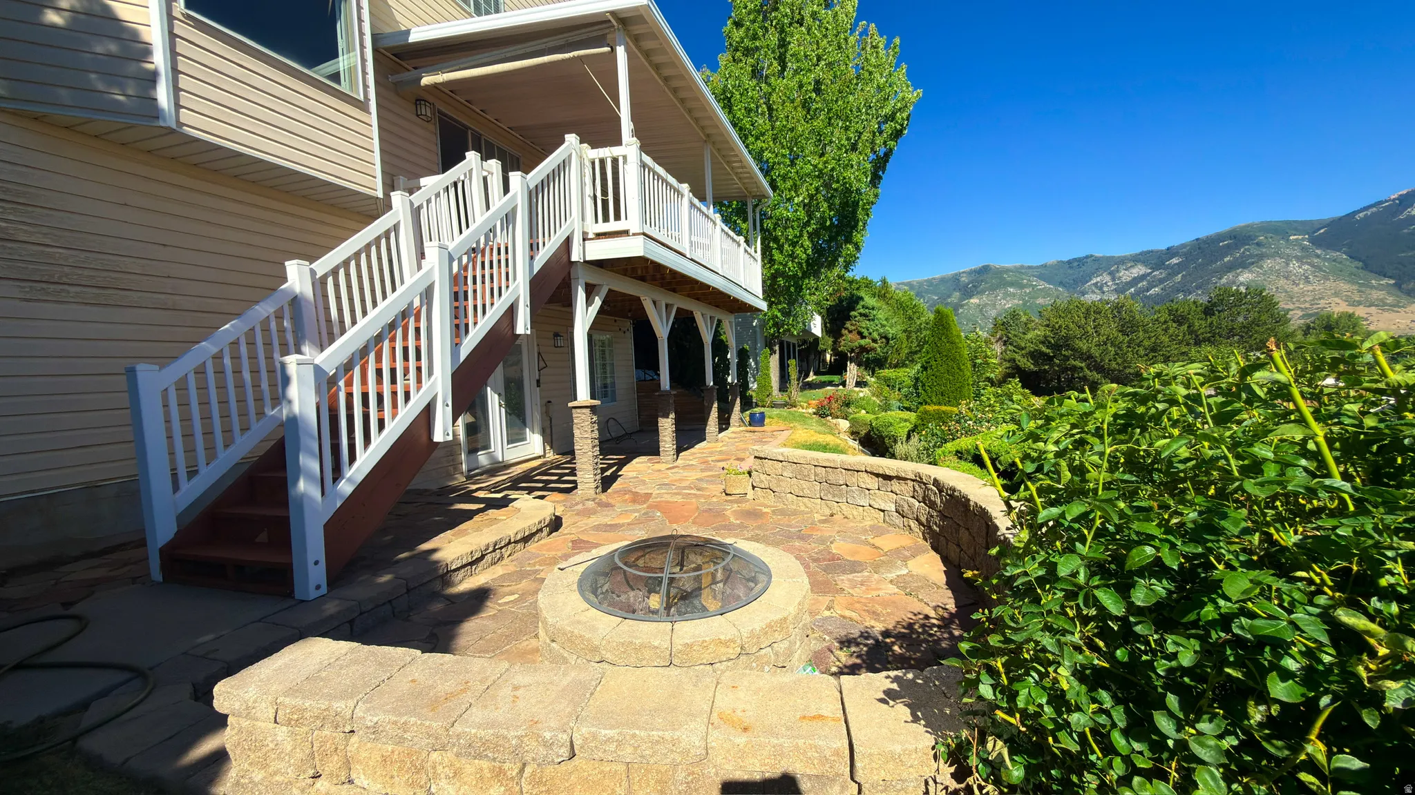 Patio area featuring a stone-clad fire pit, retaining walls, and flagstone paving