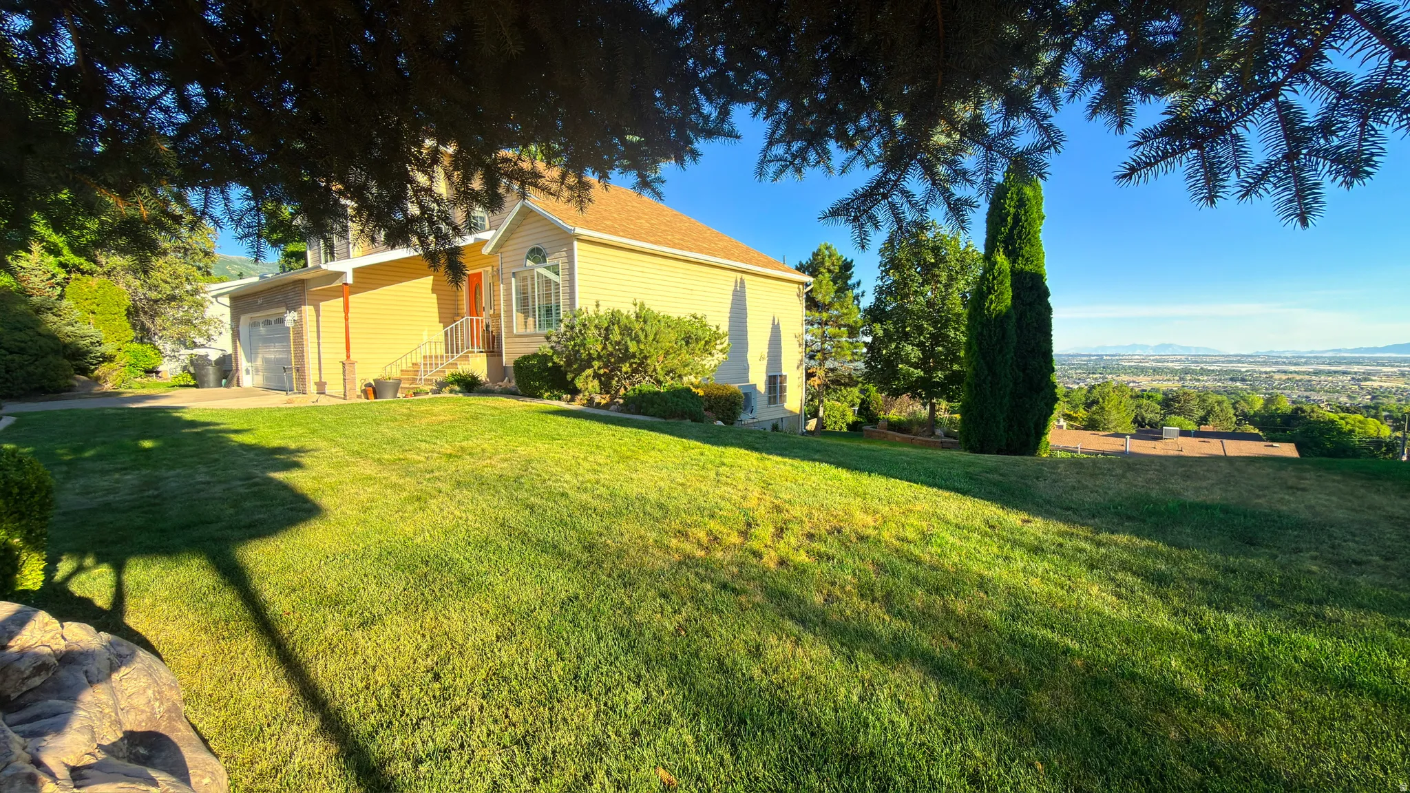 Traditional-style residence featuring a prominent garage, a bay window, and a terraced front lawn