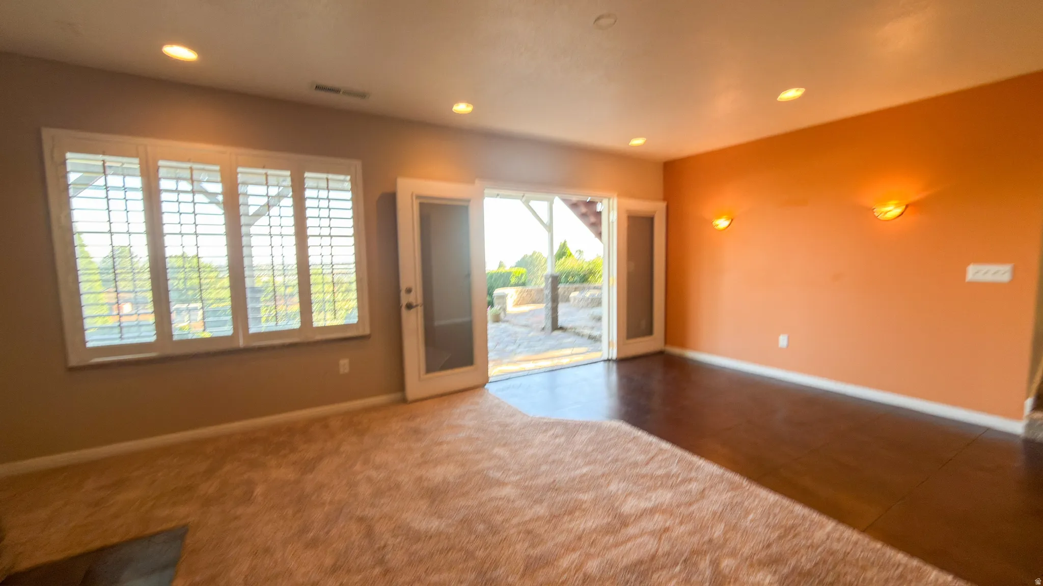 Spacious room featuring partial carpeting and dark wood-finish flooring