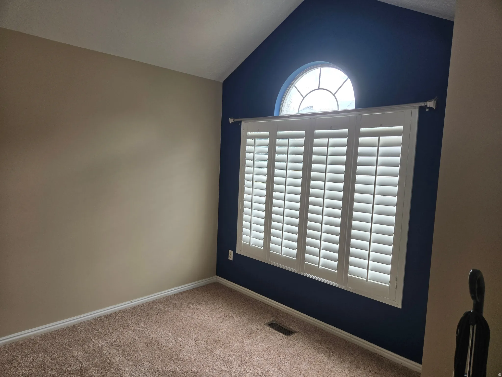 Window with white plantation shutters and an arched transom window