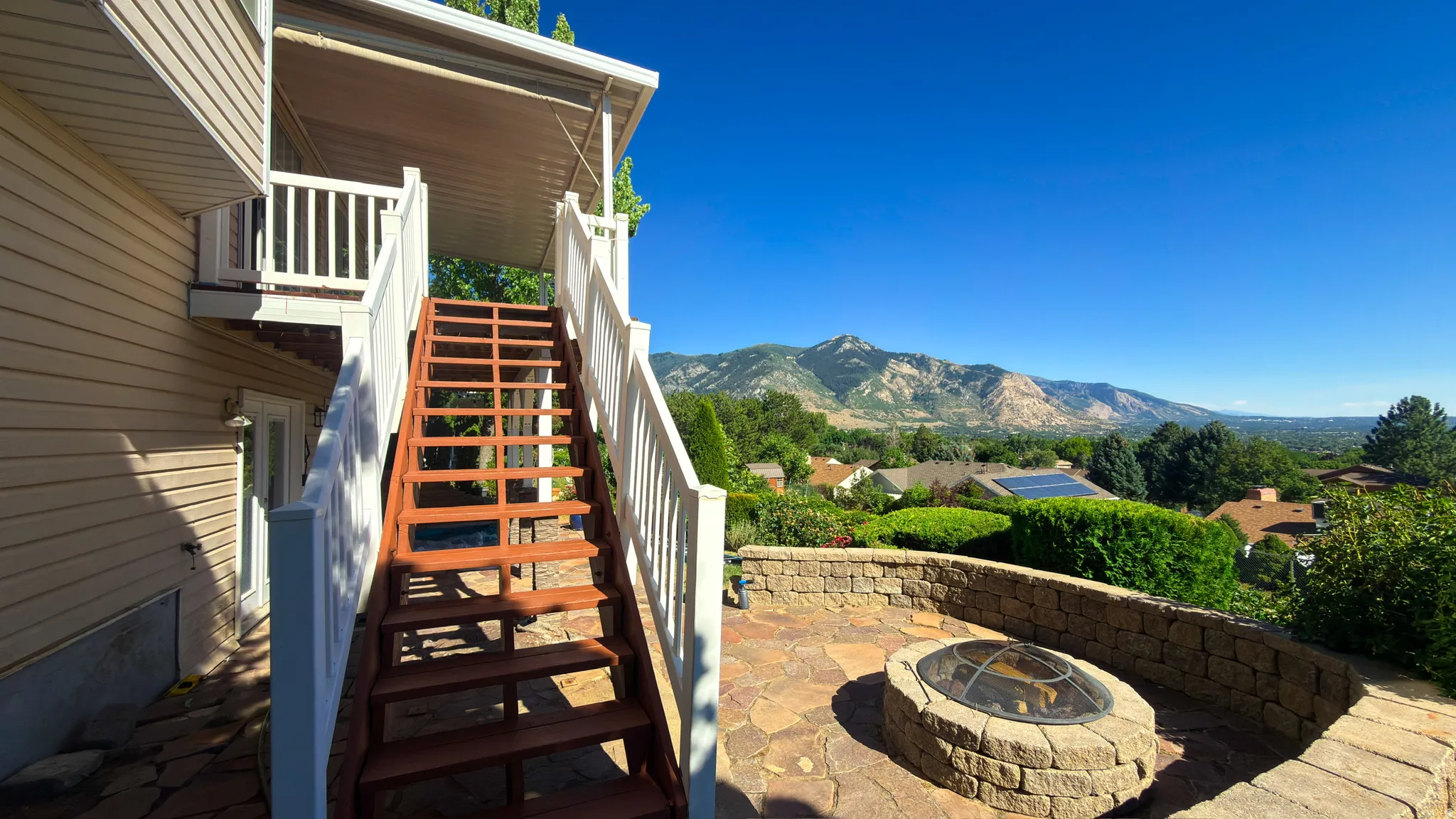 Stone fire pit with a surrounding stone wall, wood-finish stairs, and mountain scenery