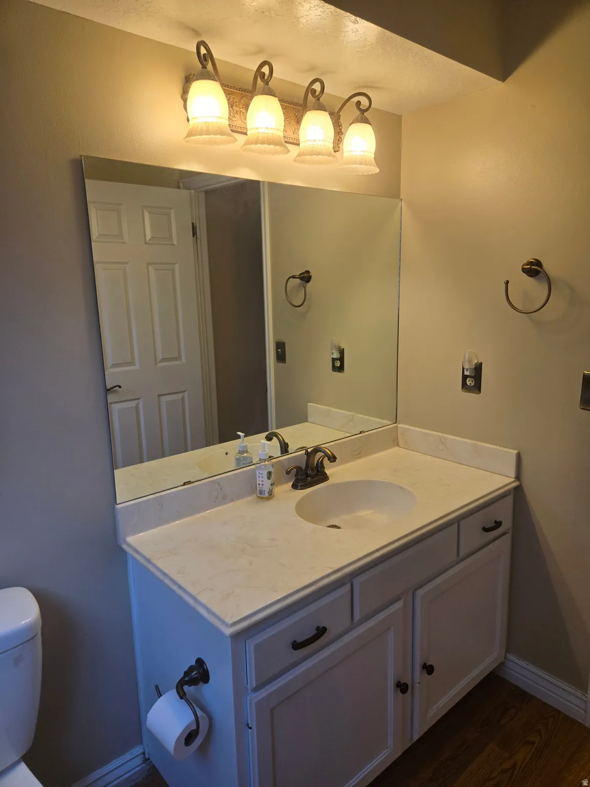Vanity with a built-in sink, an expansive mirror, and a four-light fixture