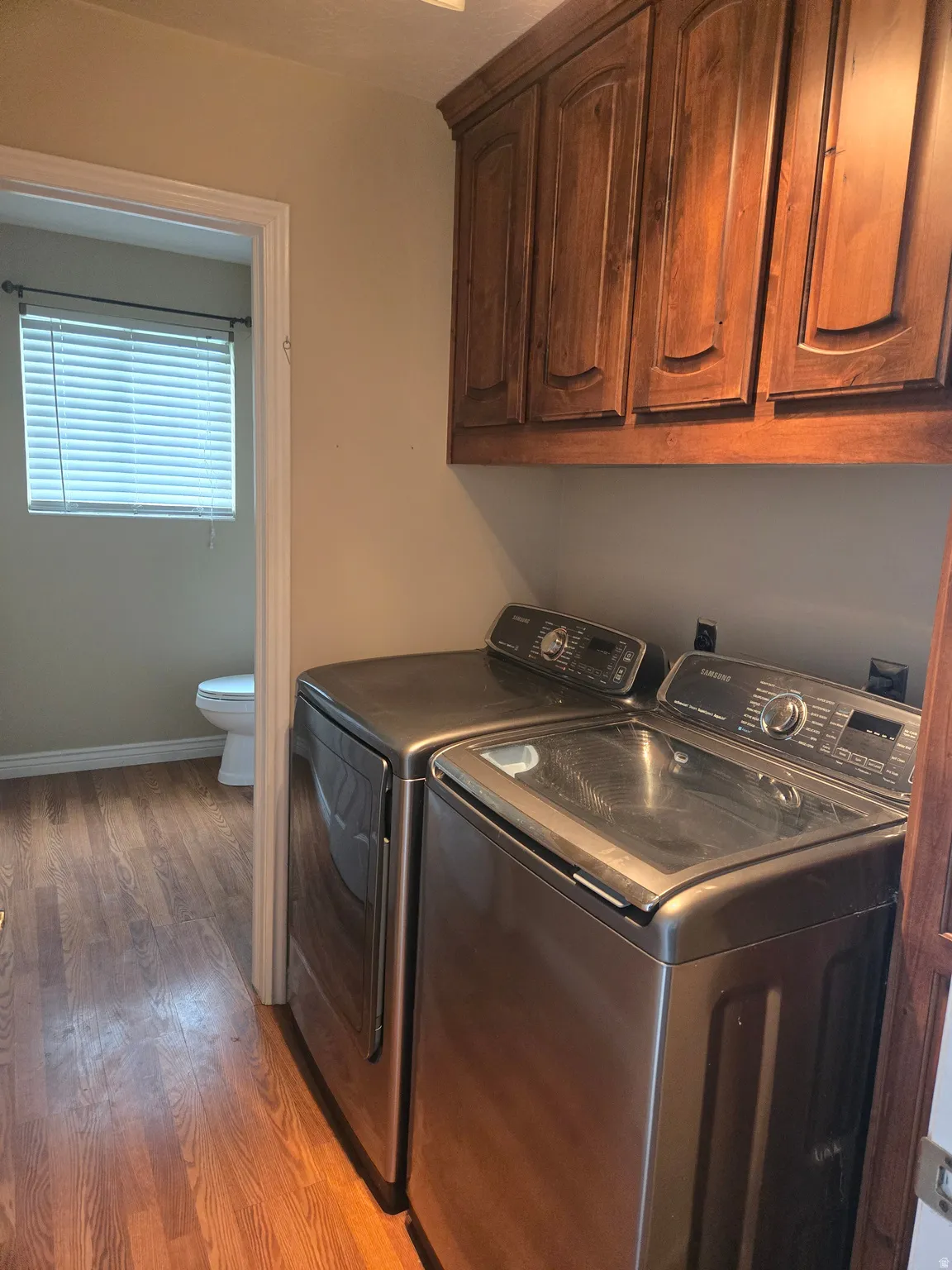 Utility area featuring wood-finish flooring and upper wood cabinetry