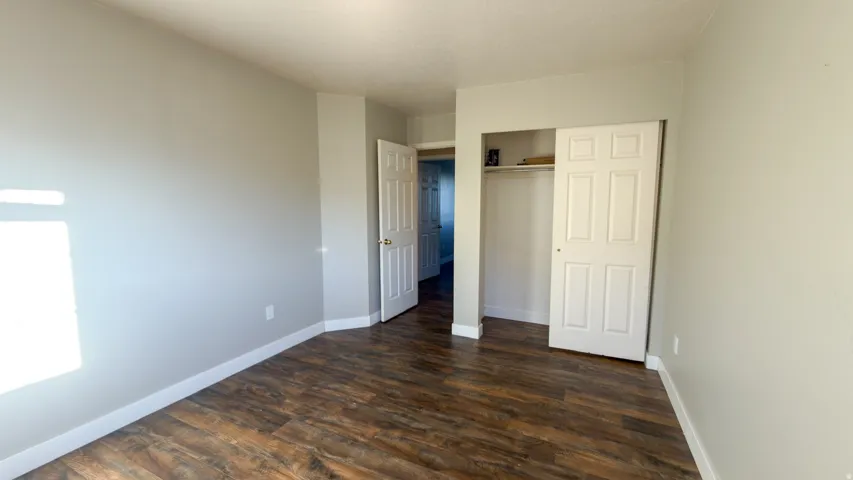 Room featuring wood-finish flooring, light gray wall paint, and white trim