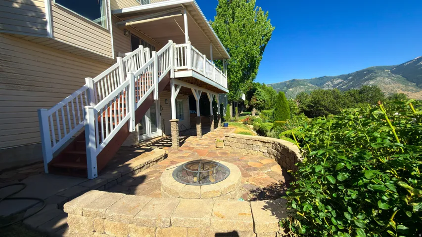Patio area featuring a stone-clad fire pit, retaining walls, and flagstone paving