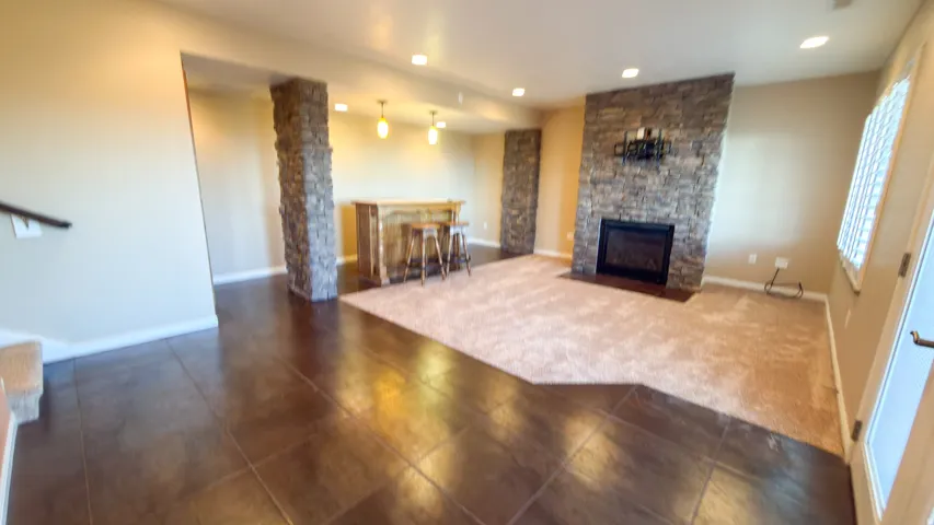 Entertainment area featuring a stone accent wall with an integrated fireplace, a built-in bar, and recessed lighting