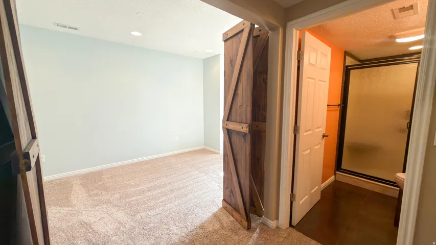 Room featuring a barn door entry, recessed lighting, and light-colored carpeting
