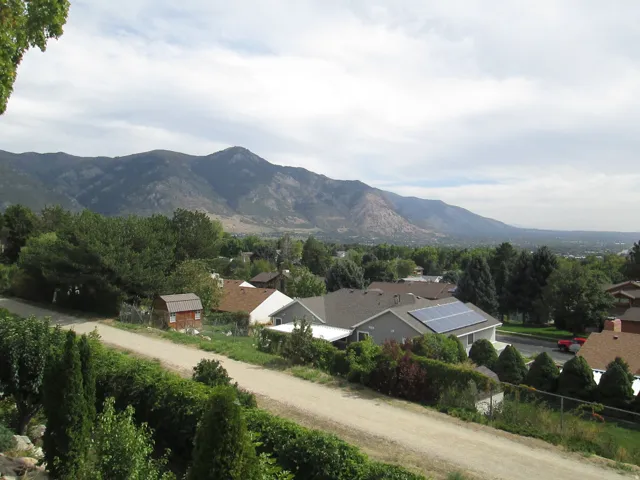 Mountain backdrop, residential area, solar panels, mature trees, landscaped greenery