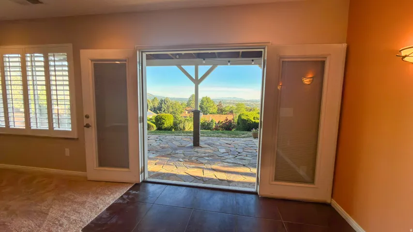 Sliding glass doors open to an outdoor patio featuring natural stone pavers and distant mountain scenery