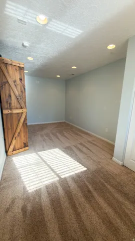 Room with textured carpet flooring and light blue wall paint
