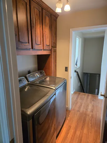 Laundry area featuring rich wood cabinetry, wood-finish flooring, and a contemporary ceiling light fixture