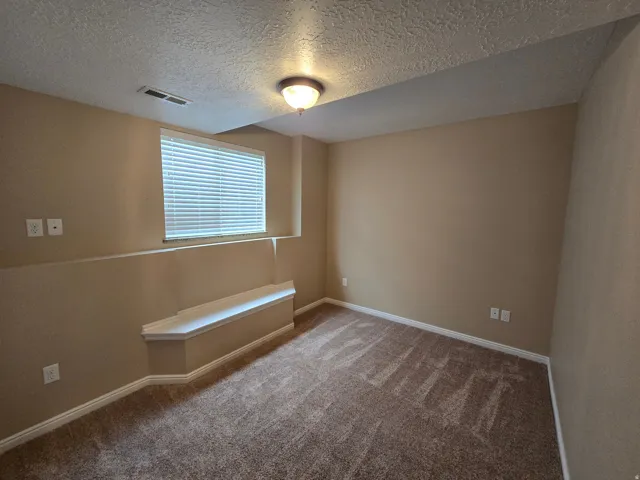 Carpeted room featuring a built-in window seat, a single window with blinds, and neutral wall tones