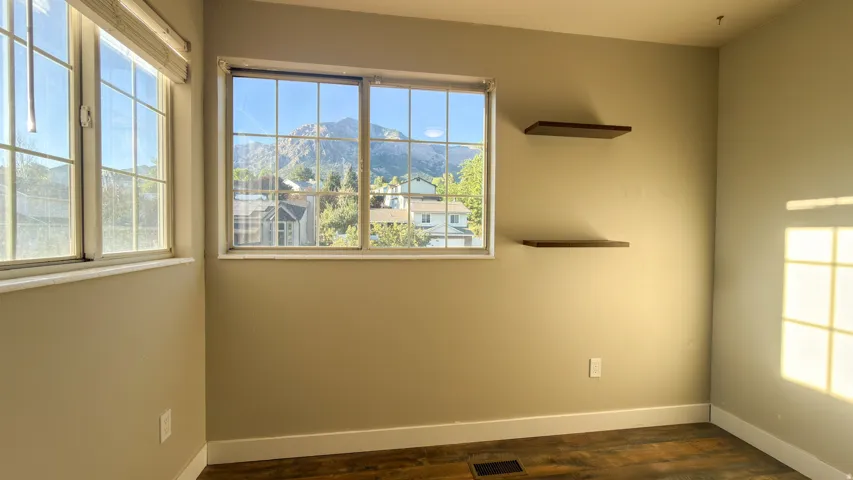 Interior space featuring wood-finish flooring, light-toned wall paint, and white baseboards