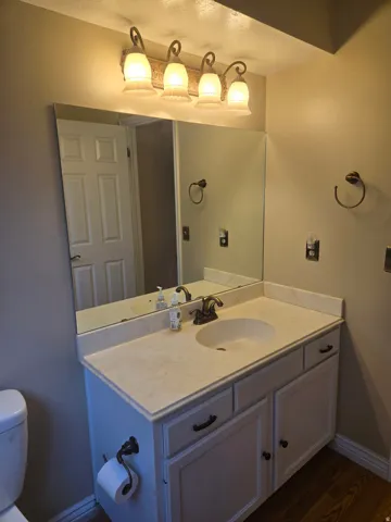 Vanity with a built-in sink, an expansive mirror, and a four-light fixture