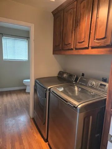 Utility area featuring wood-finish flooring and upper wood cabinetry