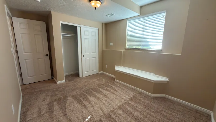 Carpeted room featuring a built-in window bench, white trim, sliding closet doors, and a six-panel door