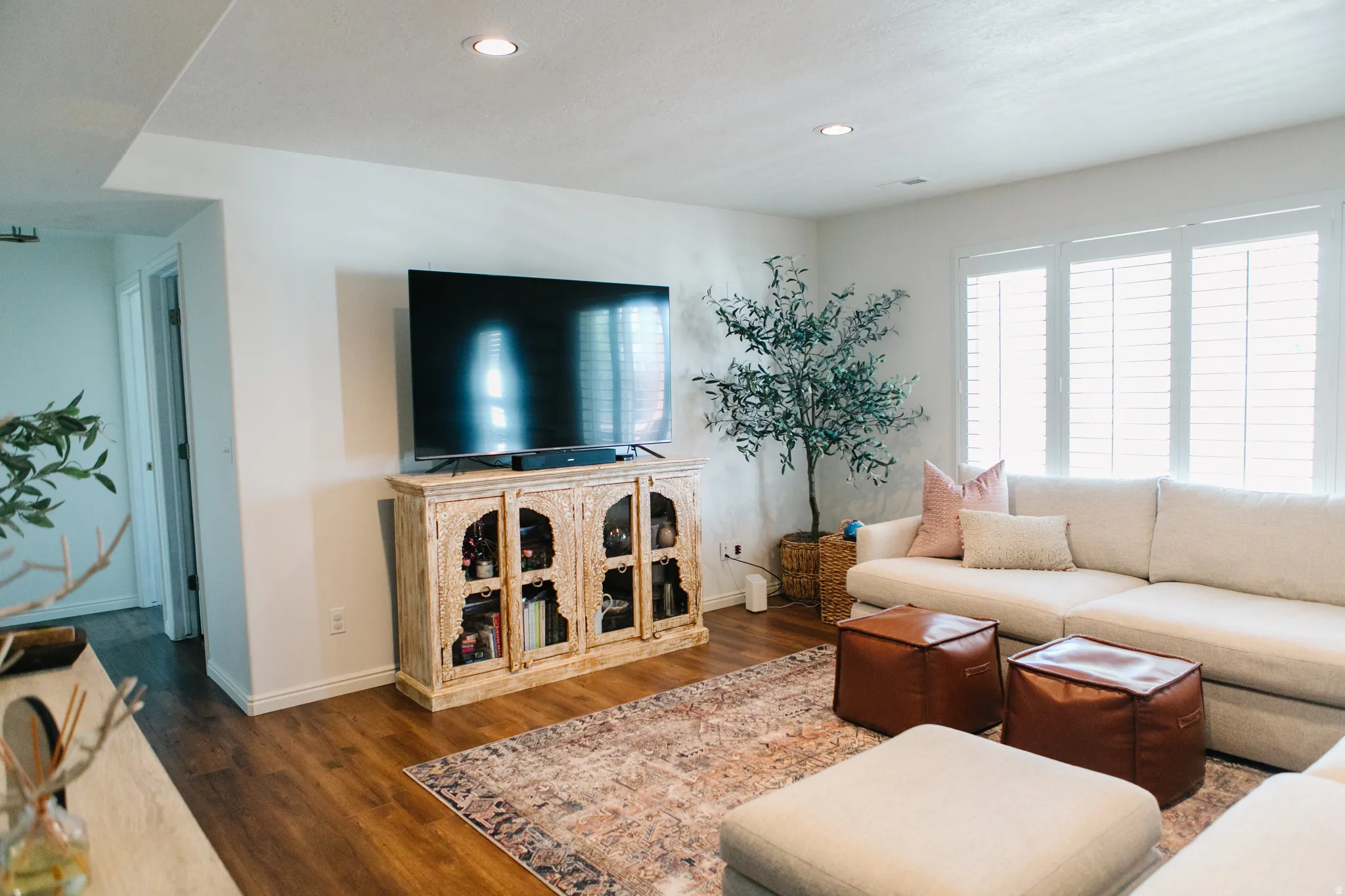 Spacious living area featuring wood-finish flooring, recessed lighting, and white plantation shutters