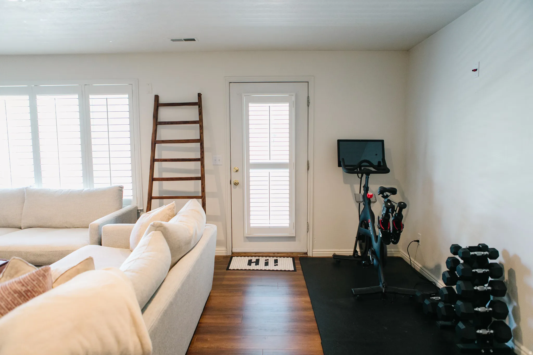 Interior space featuring wood-finish flooring, white walls, and a white door with louvered blinds