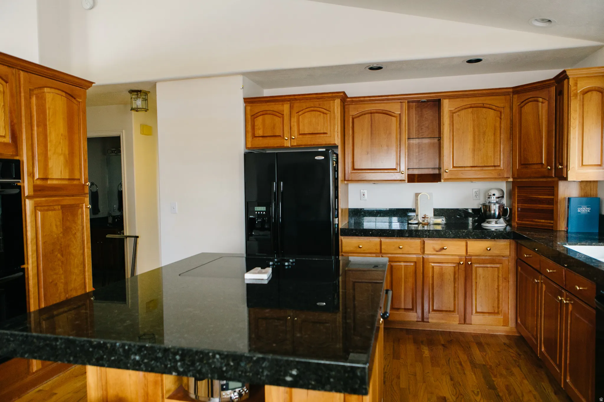 Kitchen featuring wood cabinetry, dark granite countertops, black appliances