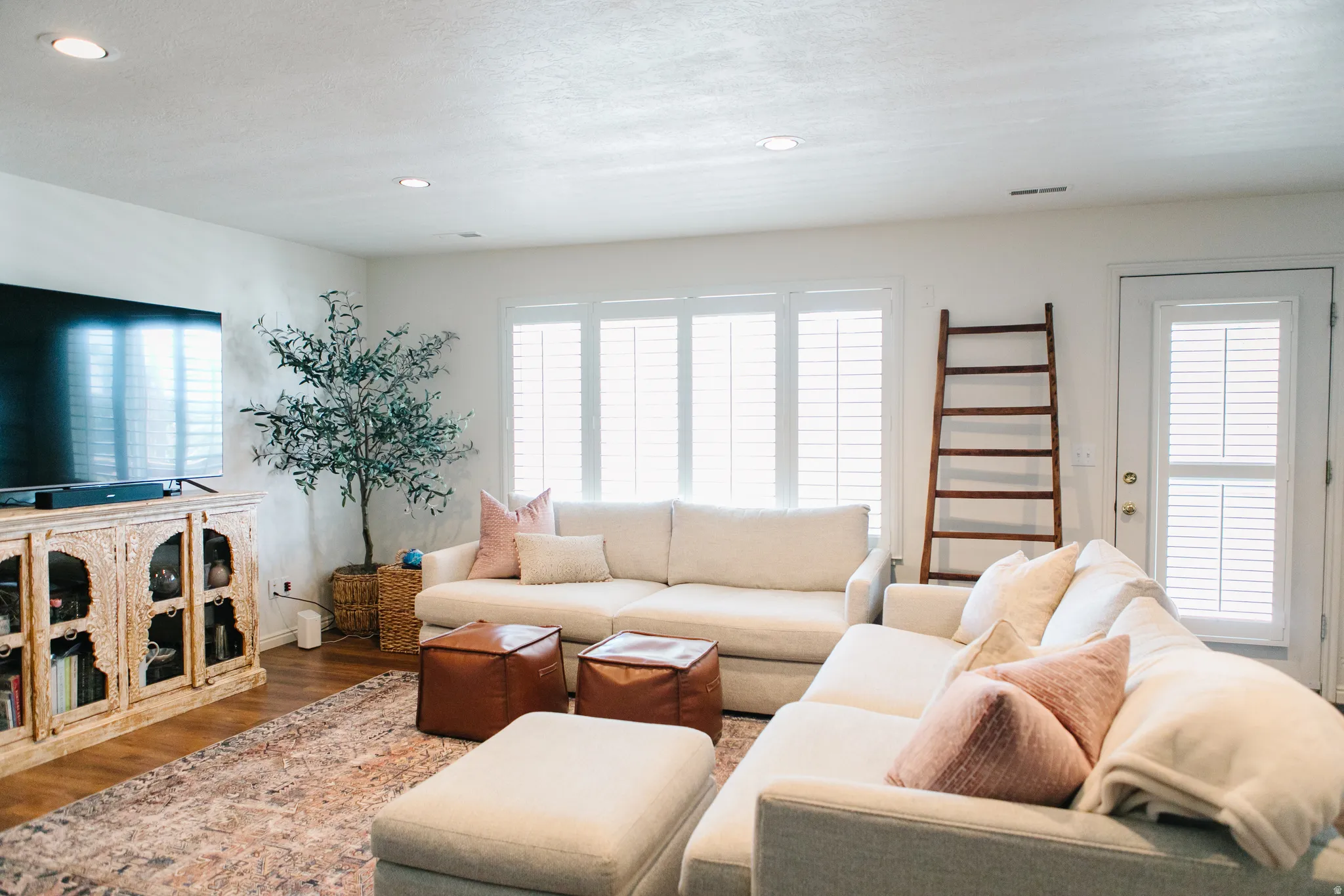 Living area featuring wood-finish flooring, recessed lighting, and white plantation shutters on windows and exterior walk out door