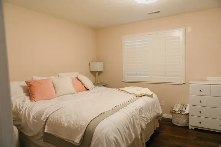 Window with white plantation shutters, light pink walls, dark wood-finish flooring, and white ceiling
