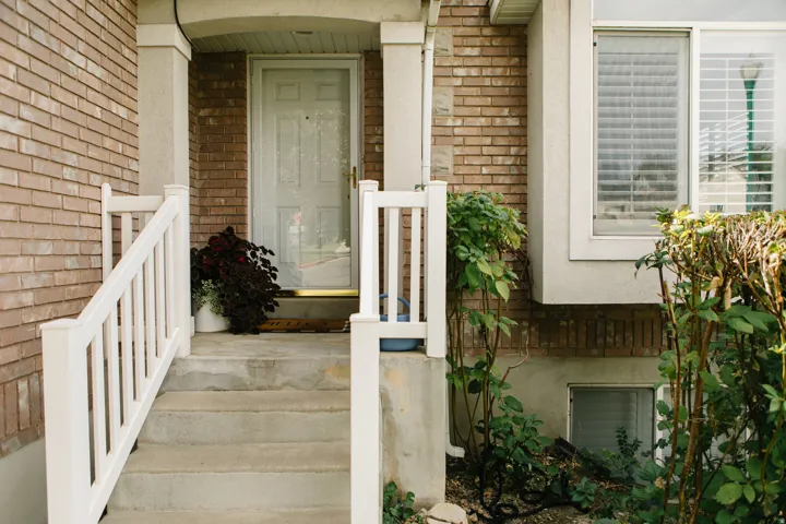 Brick entry with concrete steps and white railings