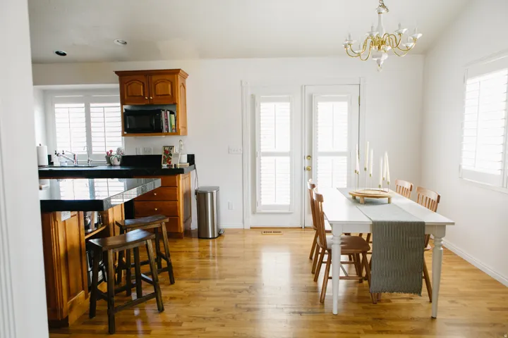 Open-concept kitchen and dining area featuring wood flooring, white walls, and a multi-light chandelier