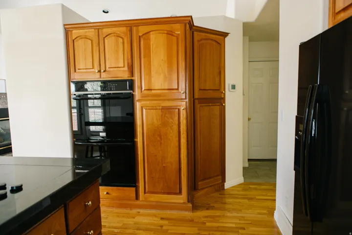 Kitchen featuring wood cabinetry, integrated double wall ovens, built-in pantry storage, and wood flooring