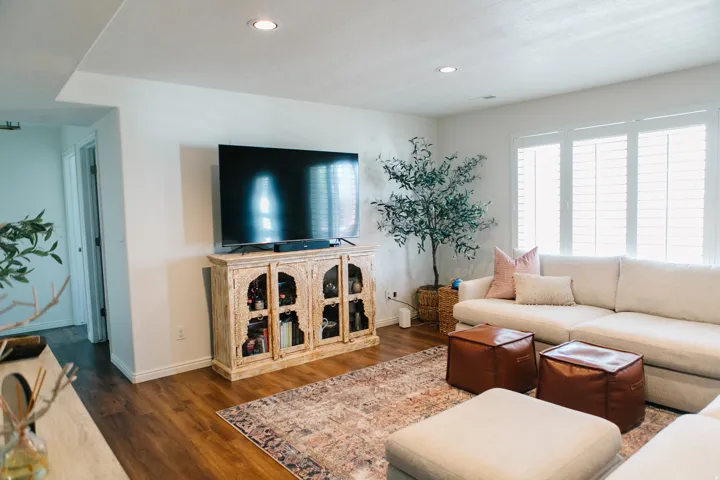 Spacious living area featuring wood-finish flooring, recessed lighting, and white plantation shutters
