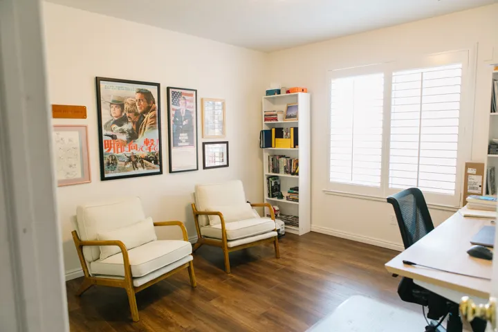 Spacious room featuring wood-finish flooring and a large window with white plantation shutters