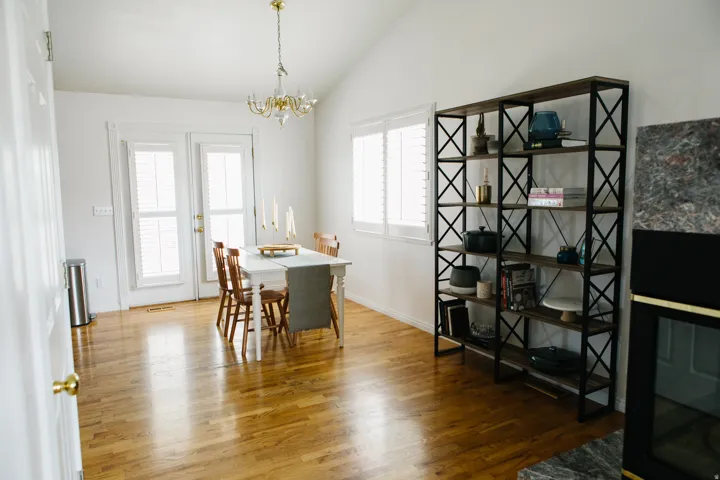 Vaulted ceiling with an elegant chandelier, wood flooring, and white plantation shutters