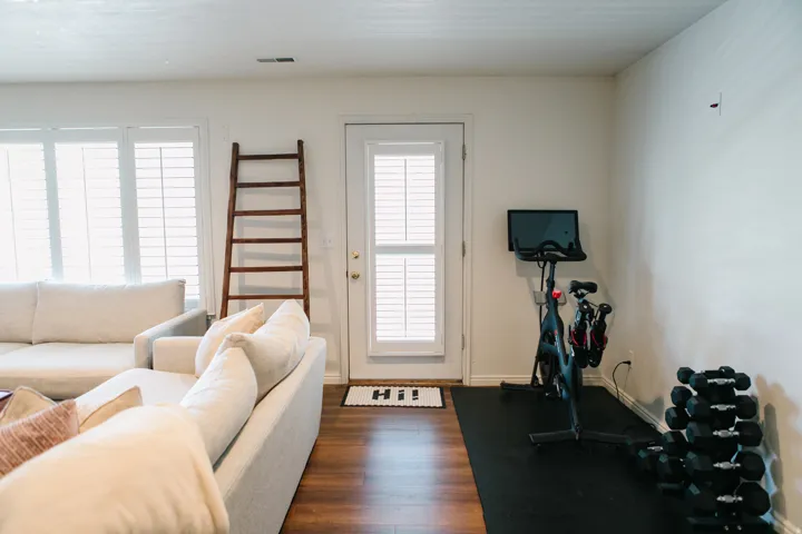 Interior space featuring wood-finish flooring, white walls, and a white door with louvered blinds