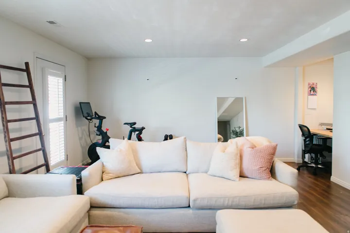 Recessed lighting illuminates this space featuring wood-finish flooring and a white paneled door with louvered blinds