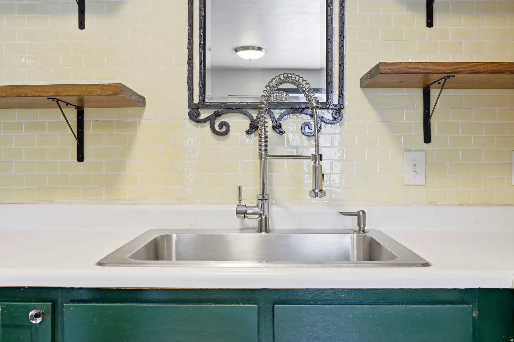Stainless steel sink with a high-arc pull-down faucet, set into a white countertop