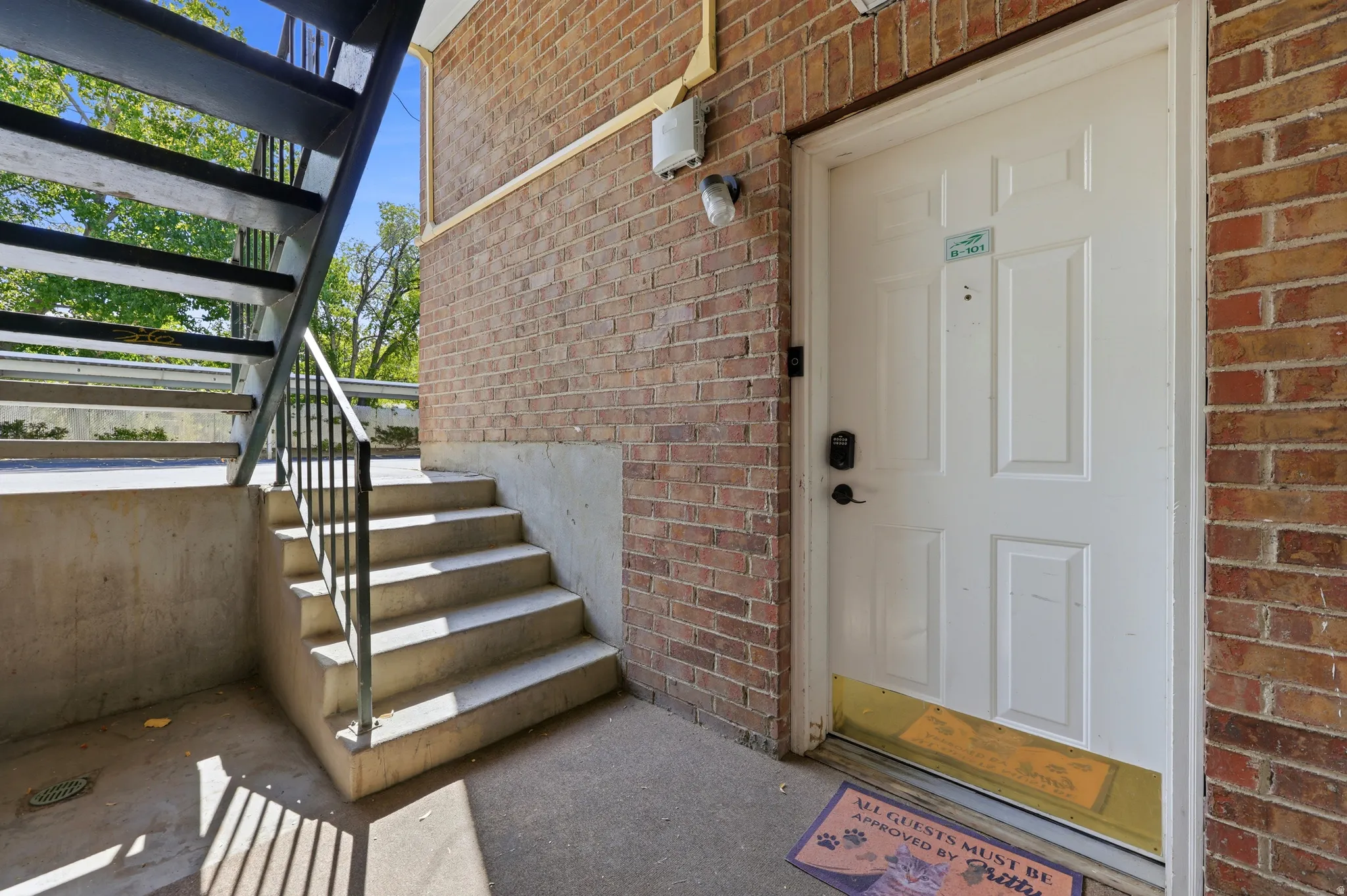 Brick exterior with white paneled entry door and metal railing