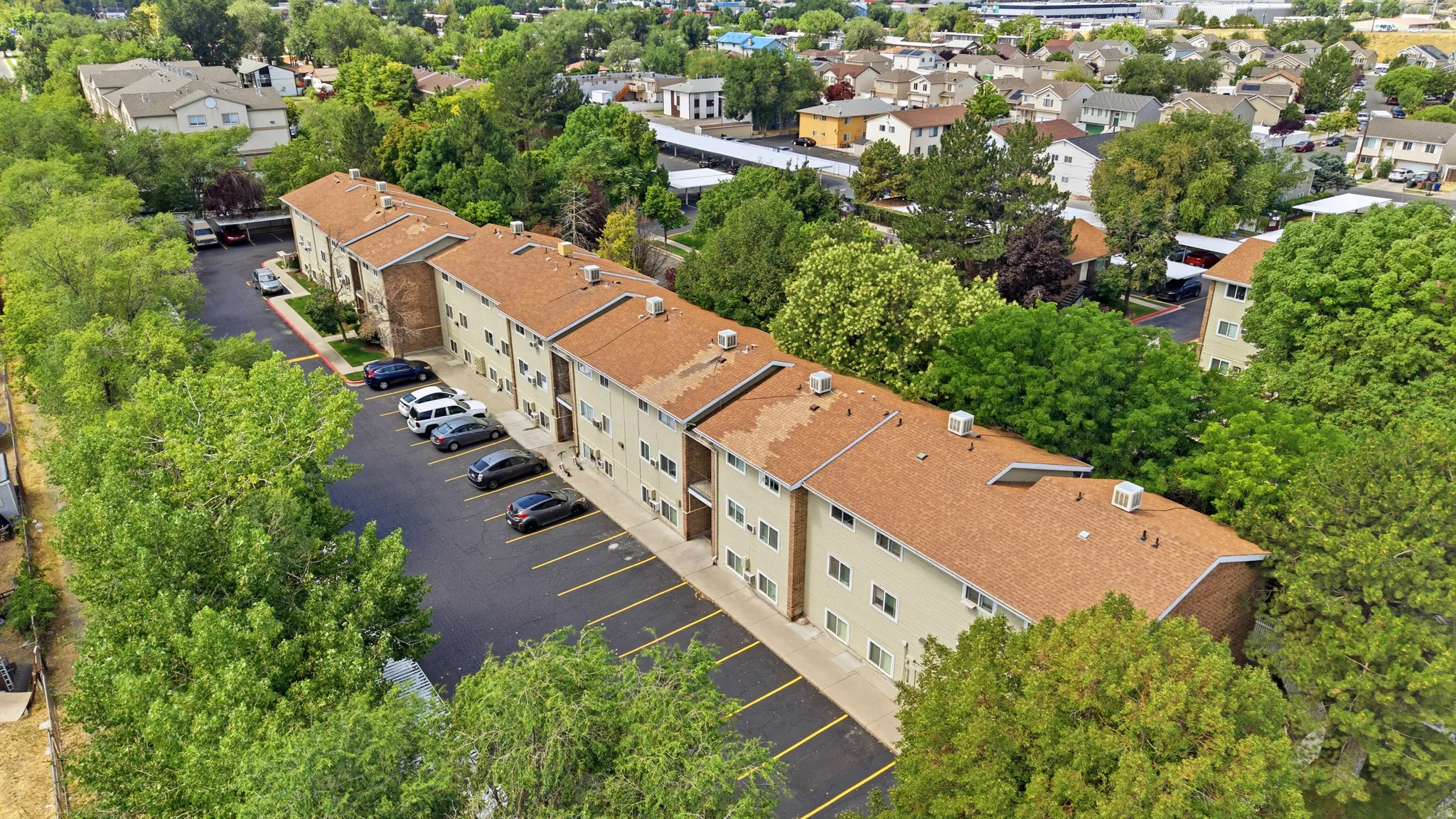 Multi-unit property featuring a brown shingle roof, light-colored siding, and brick accents