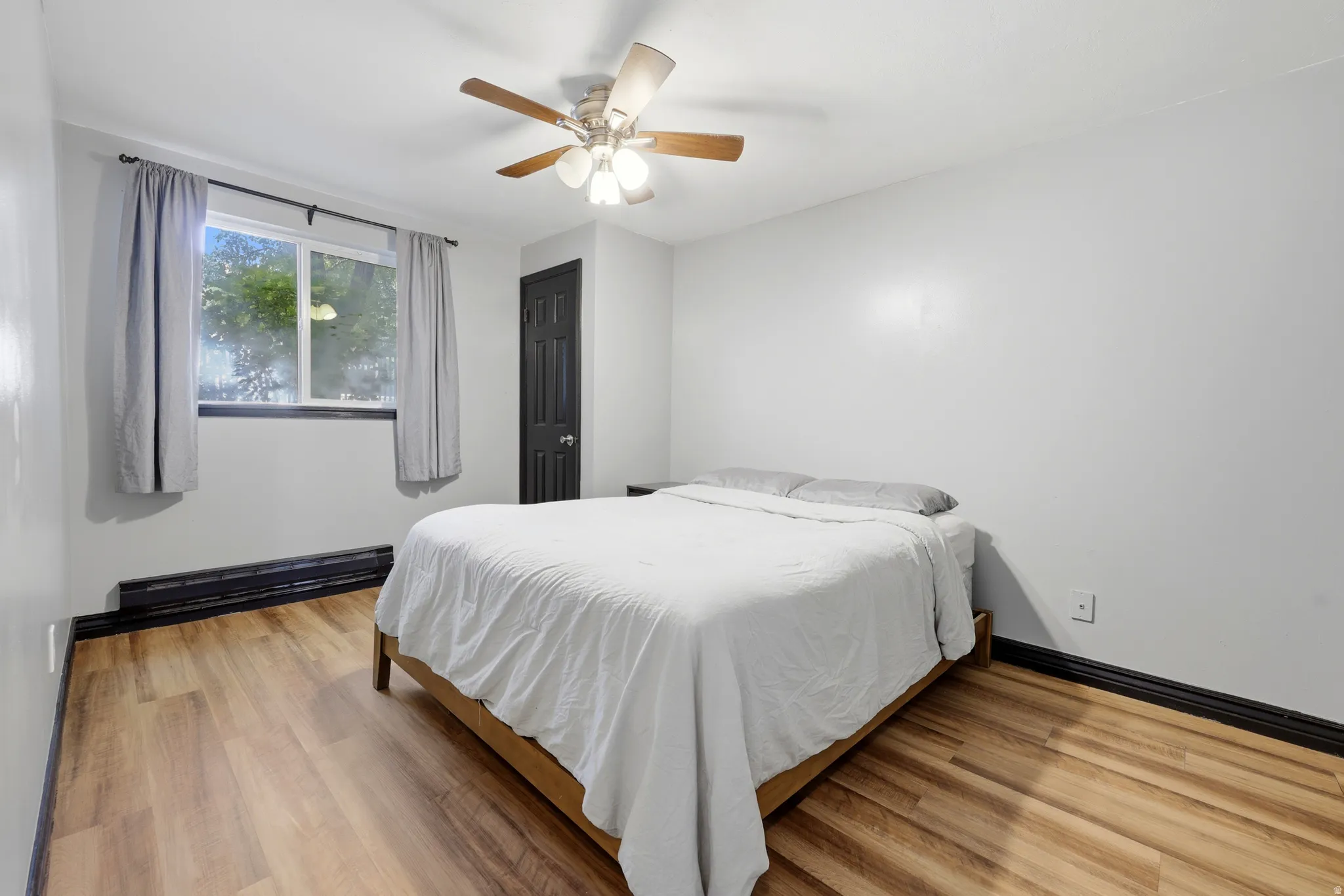 Spacious room featuring wood-finish flooring, light gray walls, and dark trim