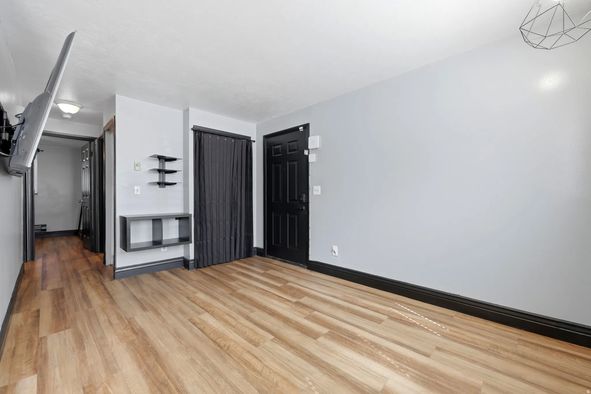 Spacious room featuring light wood-finish flooring, light gray walls, and dark baseboards