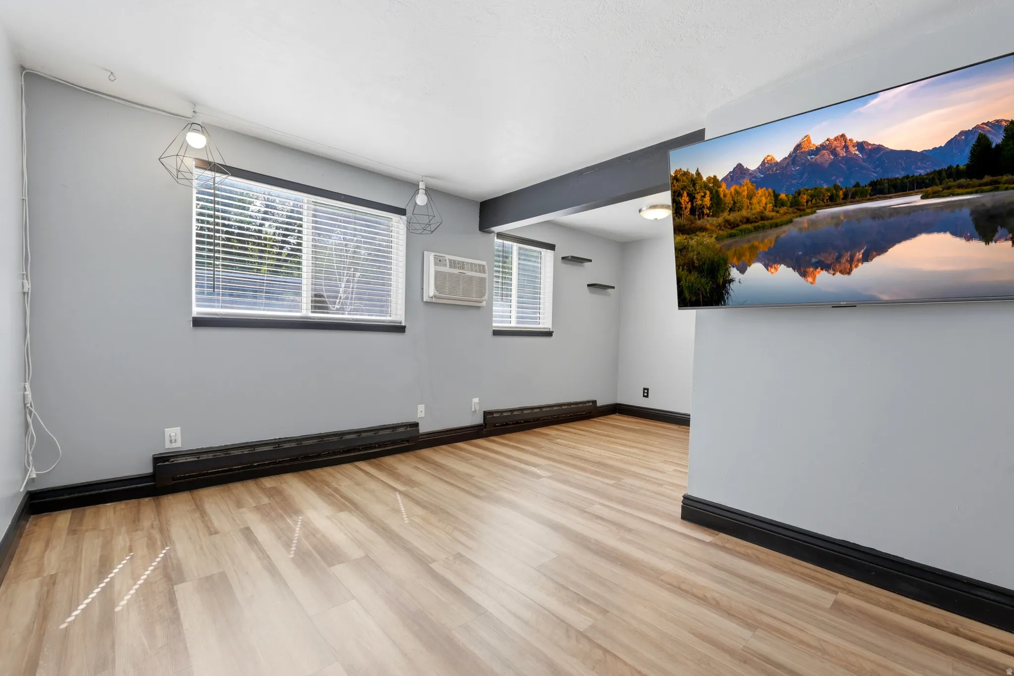Spacious interior featuring wood-finish flooring, light gray walls, and contrasting black trim