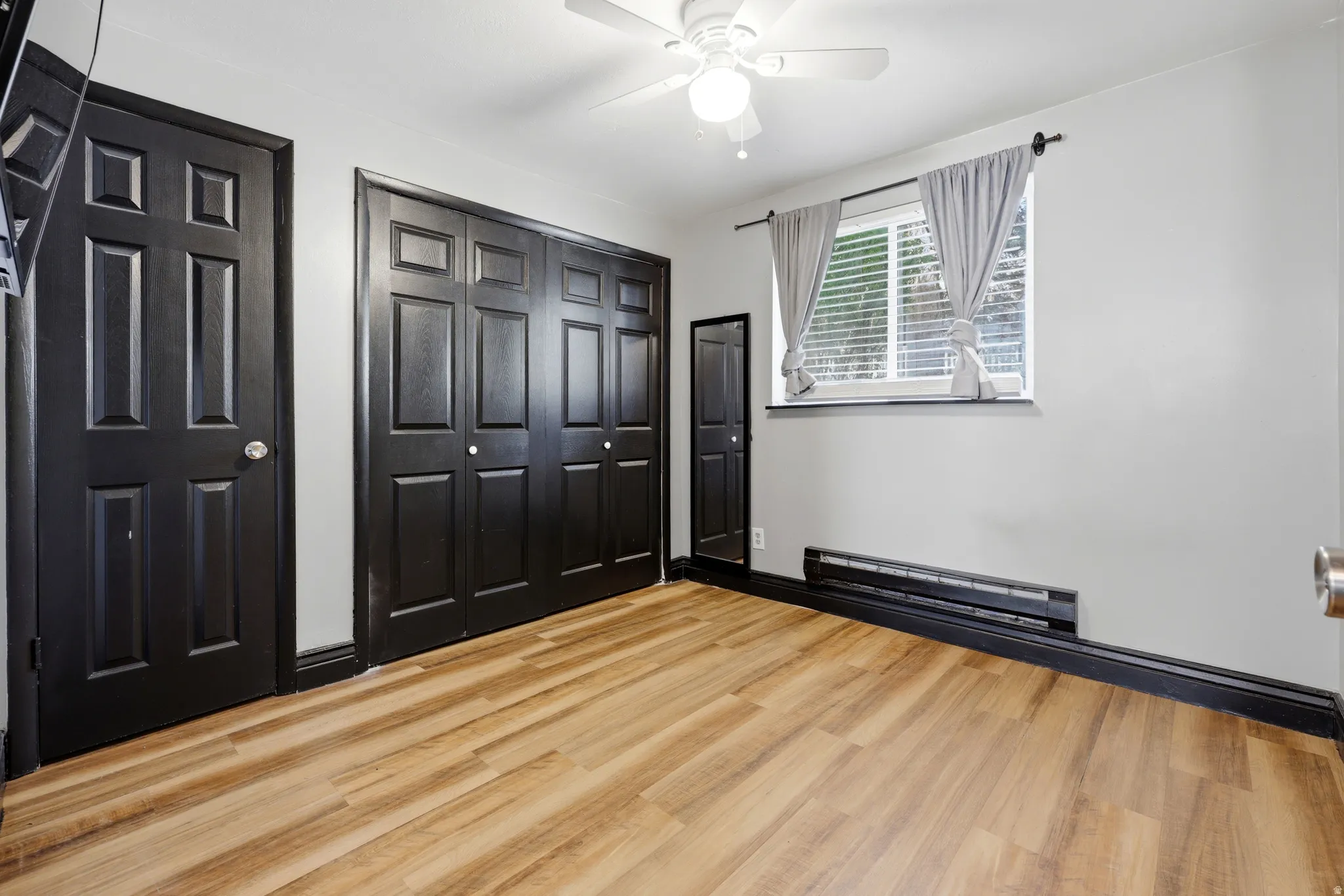 Room featuring wood-finish flooring, white walls, and dark trim